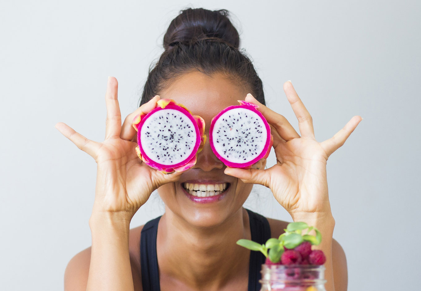 Healthy Vision - woman grinning holding round fruit over her eyes