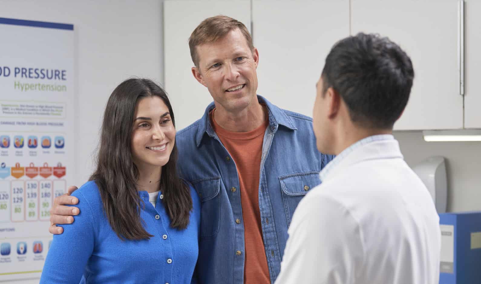 A patient and a visitor talking to a healthcare professional in a medical office setting, promoting healthcare services and patient engagement.