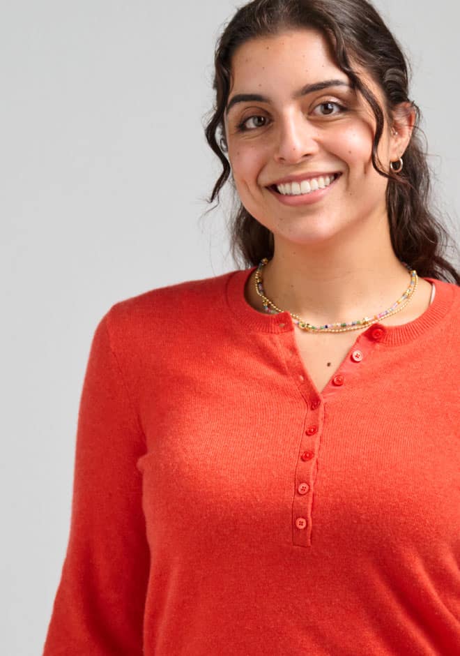Smiling woman with dark curly hair wearing a red top, representing health and wellness, suitable for healthcare and medical group themes.